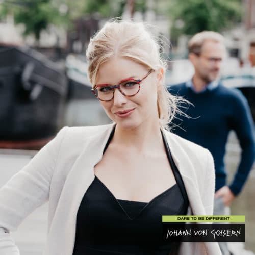 Woman wearing black top and white jacket with coloureful Johann Von Goisern glasses.