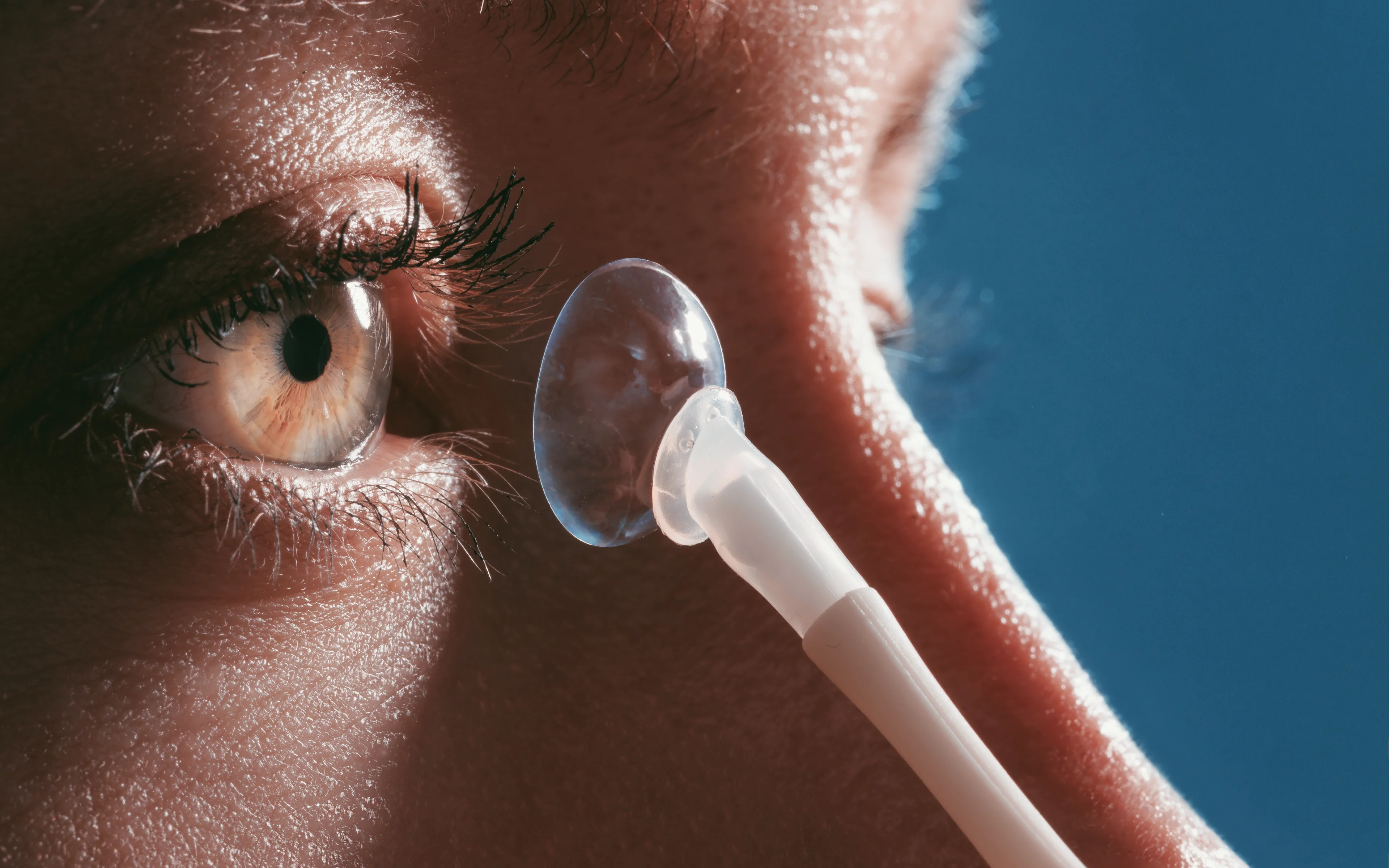A scleral contact lens held near an eye.