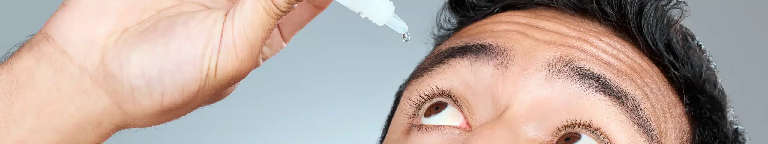 A patient uses eye drops after a glaucoma eye test.