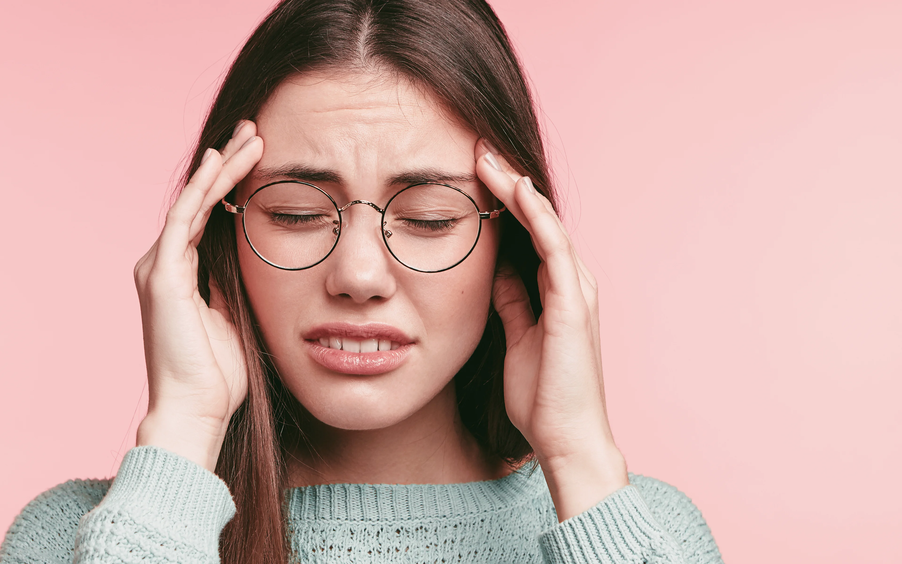A young female with hands near eyes, suffering eyestrain.