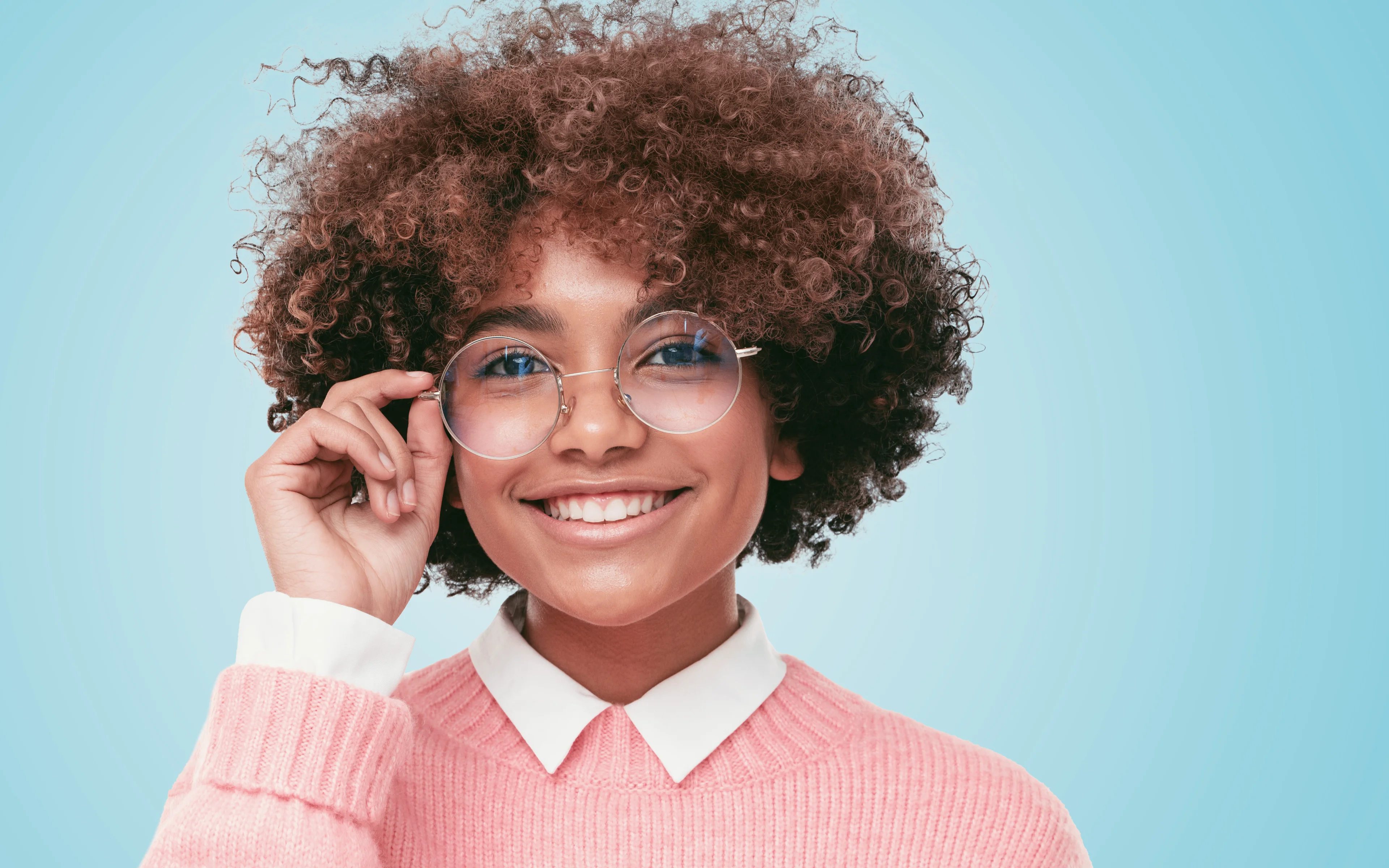 A smiling teenage girl wearing glasses.