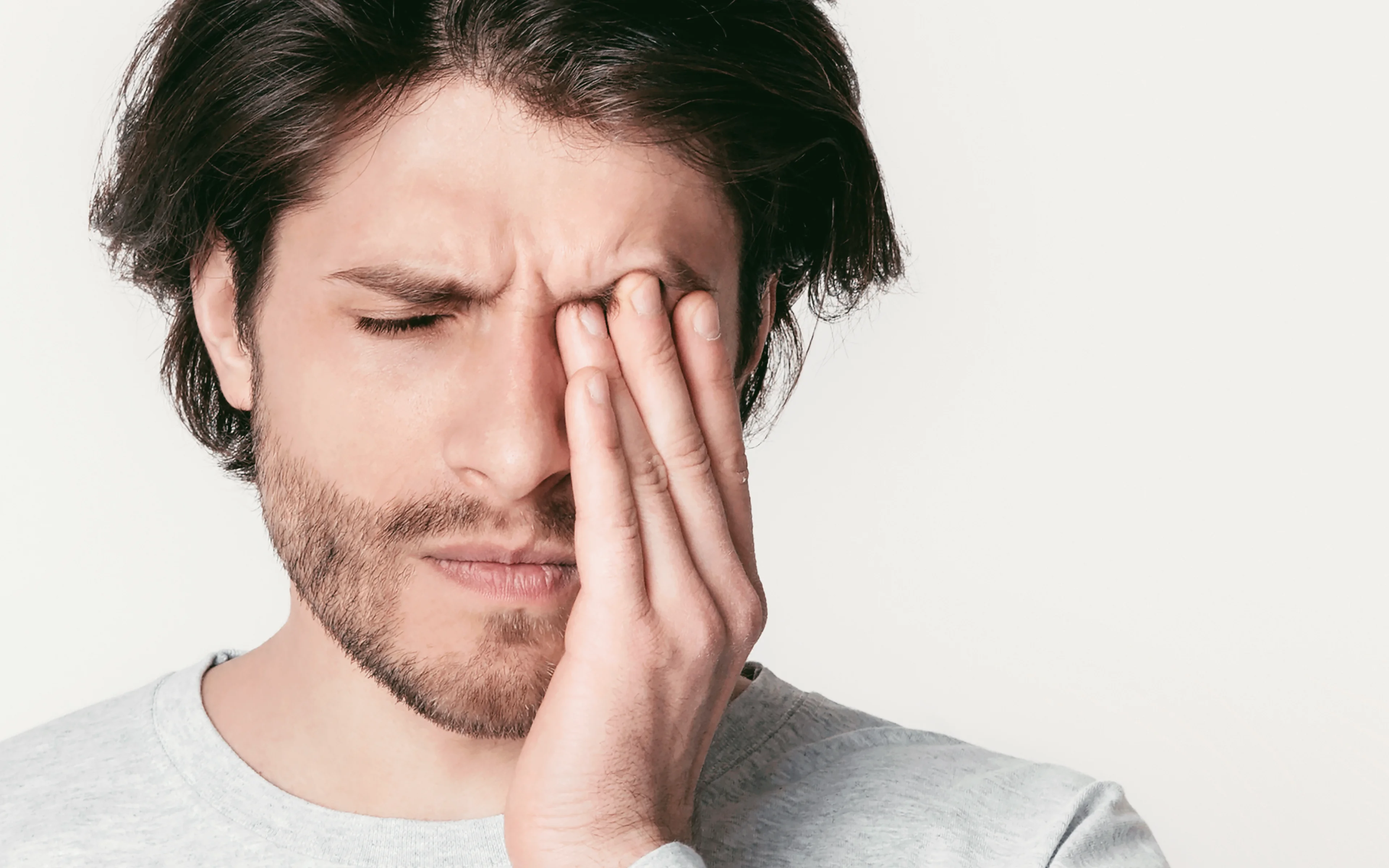 Man rubs his eyes, suffering from dry eye diesease.