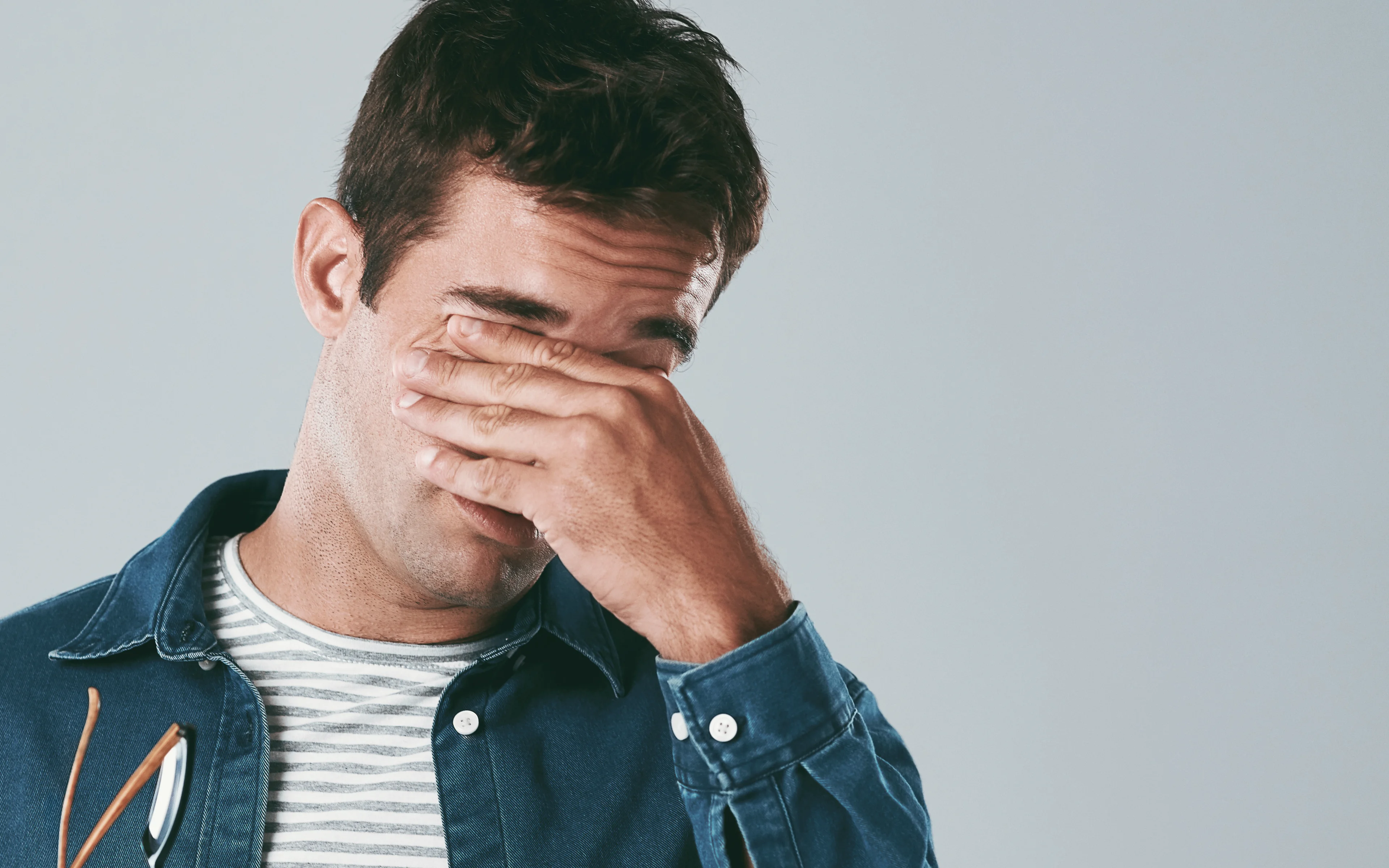 A young male with hands over eyes, suffering eyestrain.