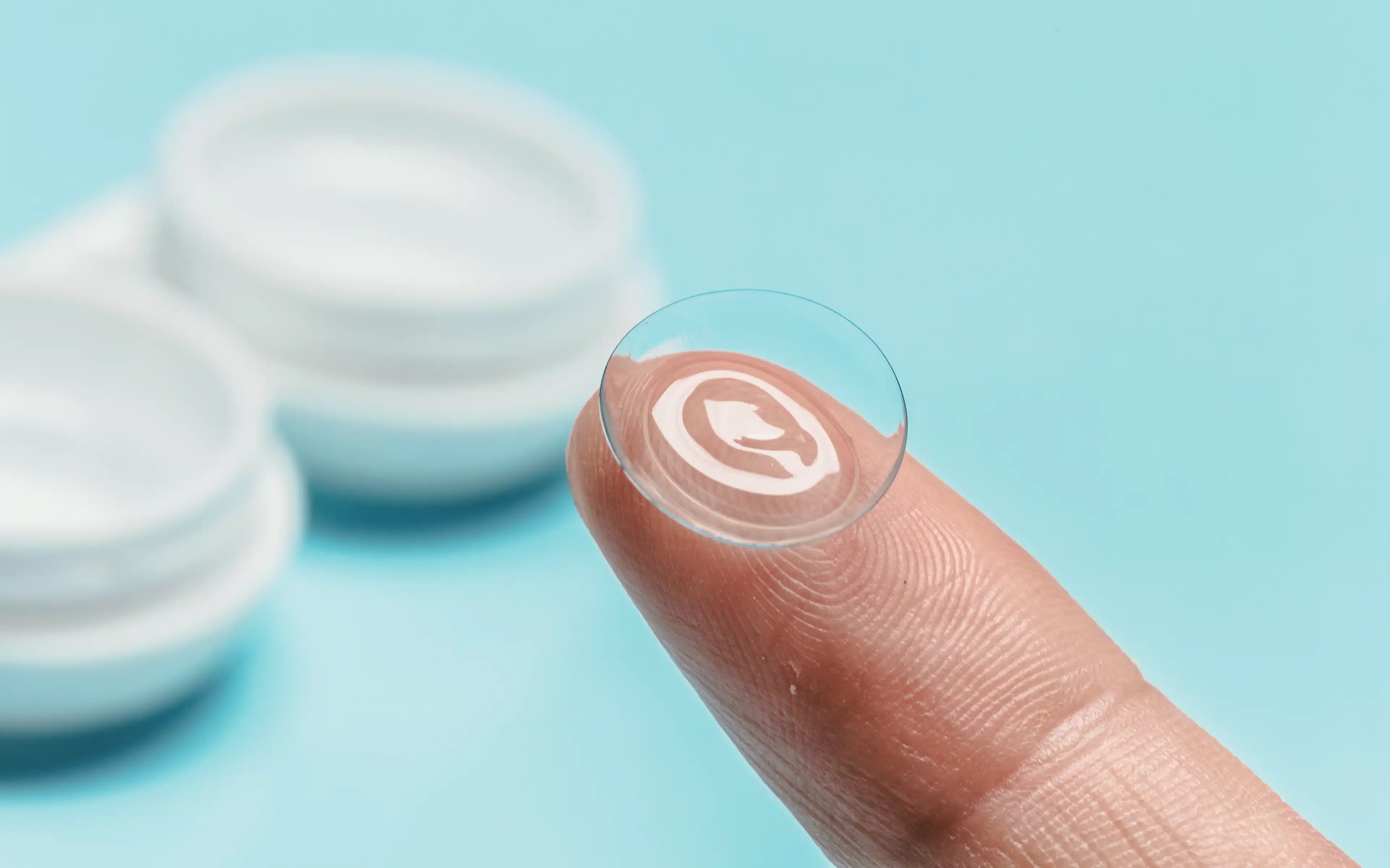 A hybrid contact lens resting on a fingertip.