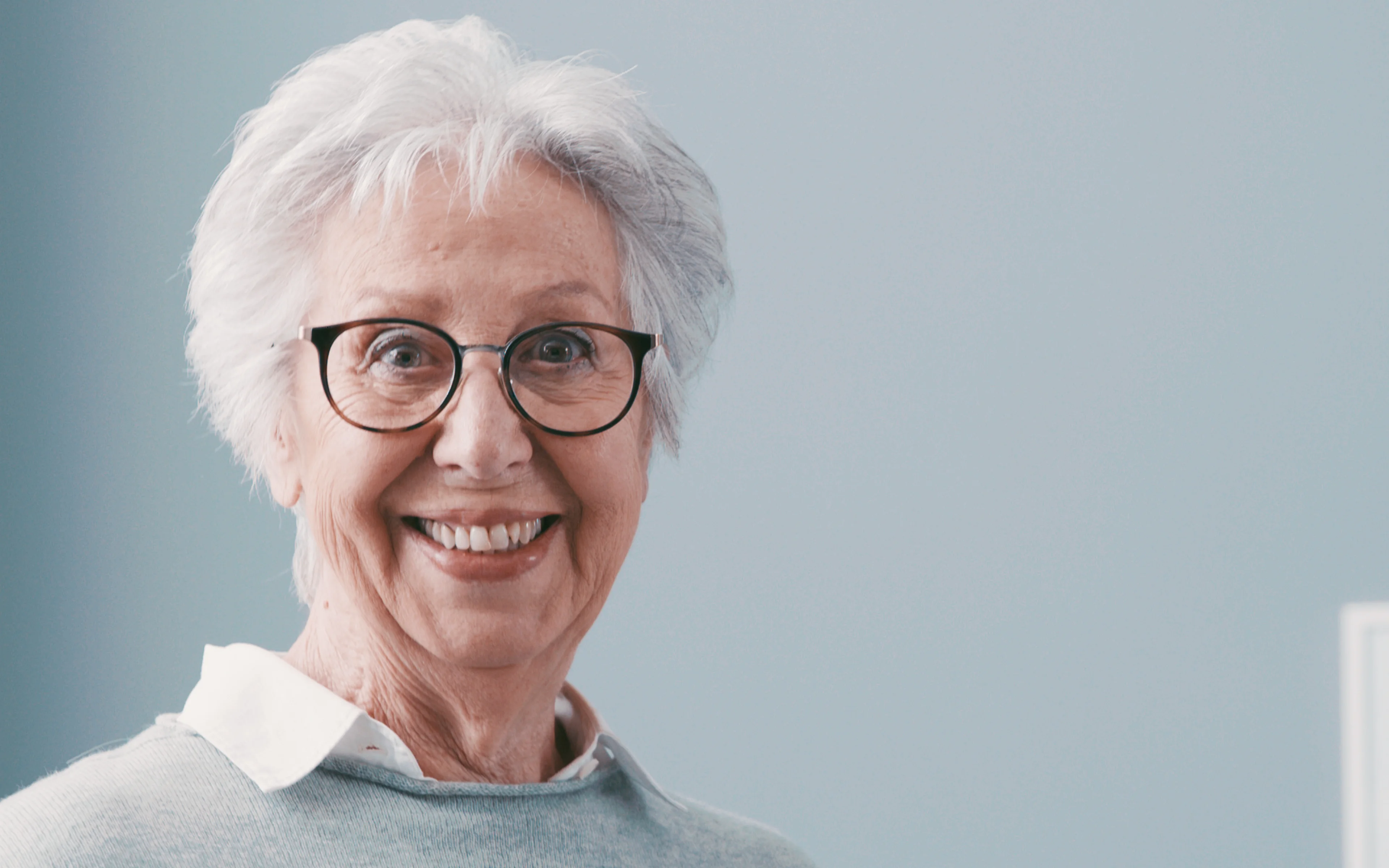 An elderly female smiling and wearing glasses.