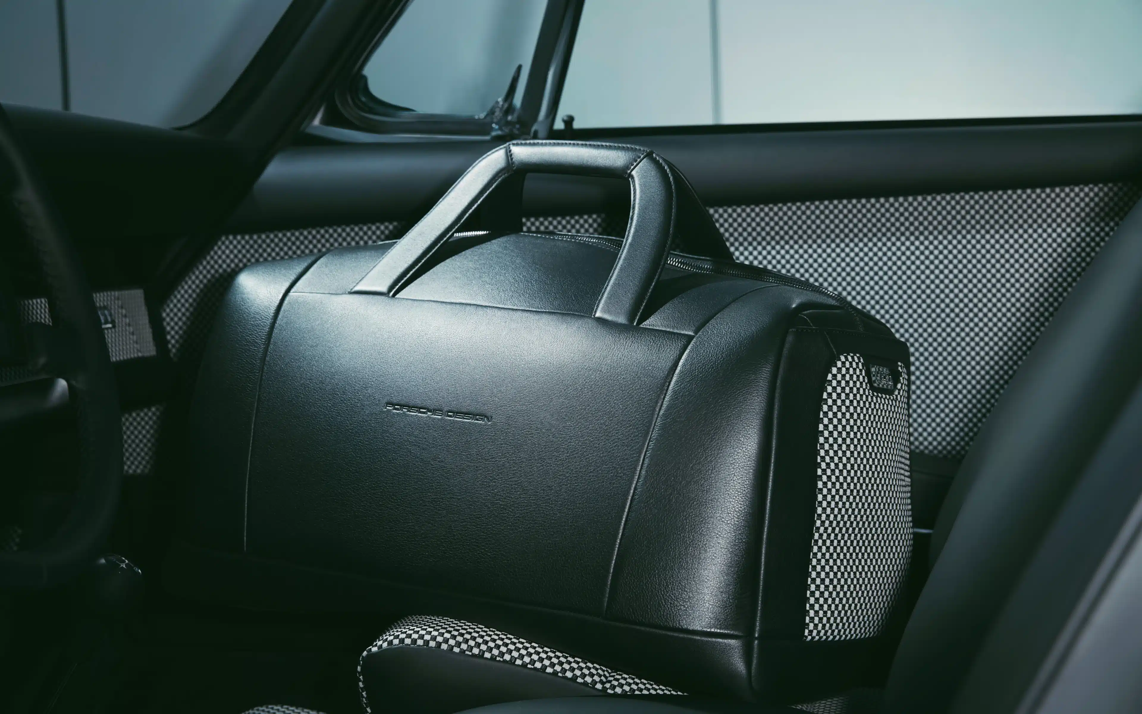 A Porsche branded carry bag on the saet of a motor vehicle.