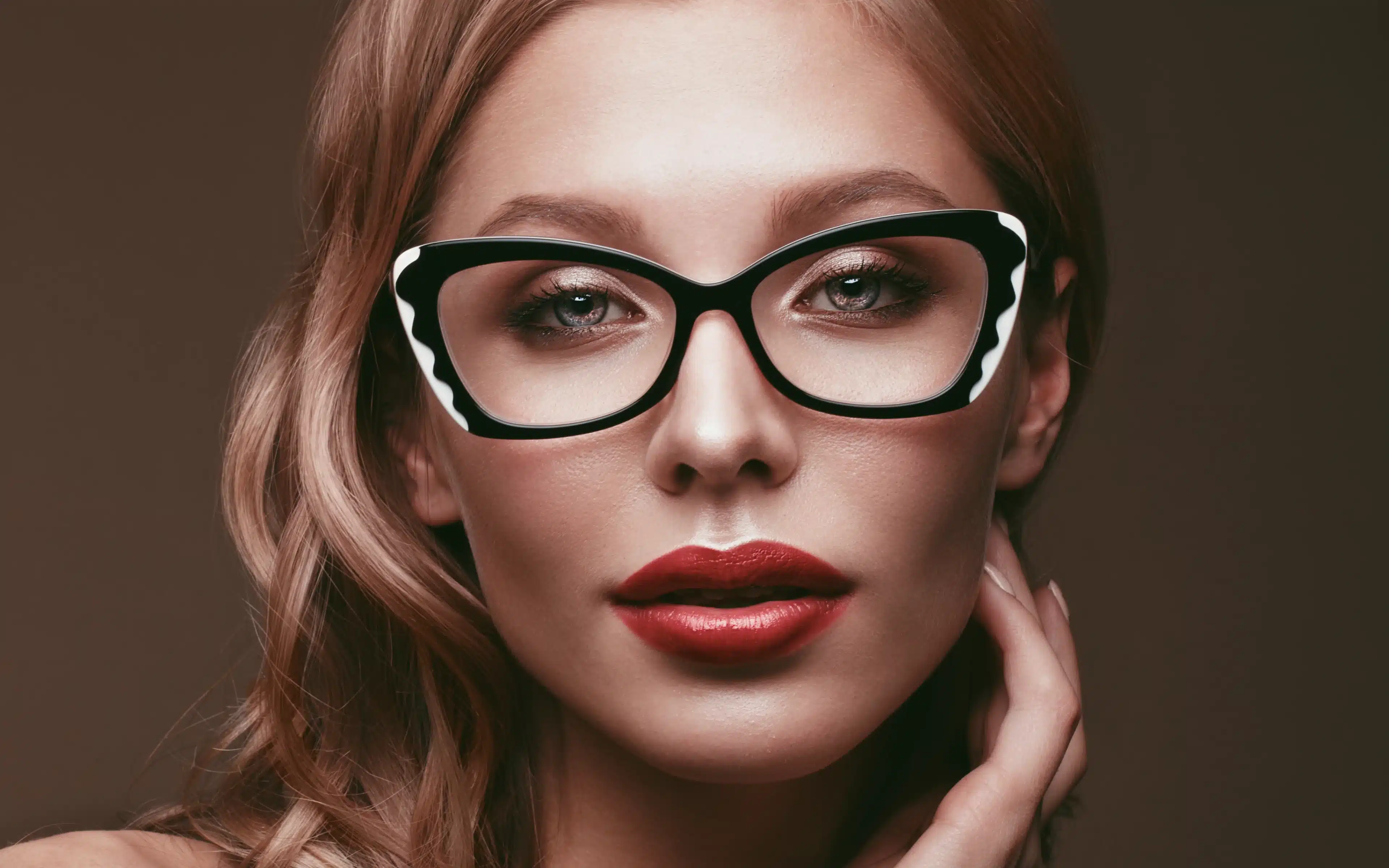 Woman with red lipstick wearing fashionable glasses.